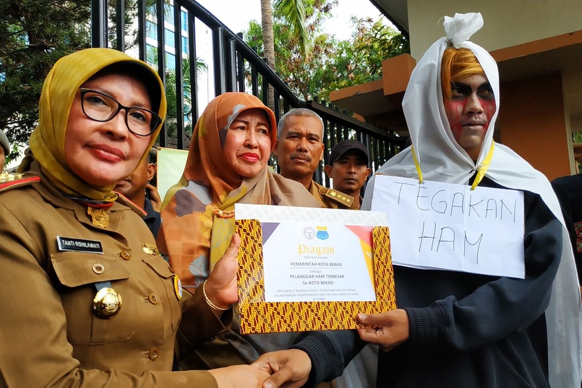 Aksi simbolik penyerahan piagam penghargaan kepada Pemerintah Kota Bekasi oleh mahasiswa PMII sebagai pelanggar HAM terbesar se-Kota Bekasi, Selasa (10/12/2019) bertepatan dengan hari HAM Internasional. Predikat itu disematkan mahasiswa akibat kasus-kasus KDRT, pelecehan perempuan dan anak, dan penggusuran paksa di Kota Bekasi.