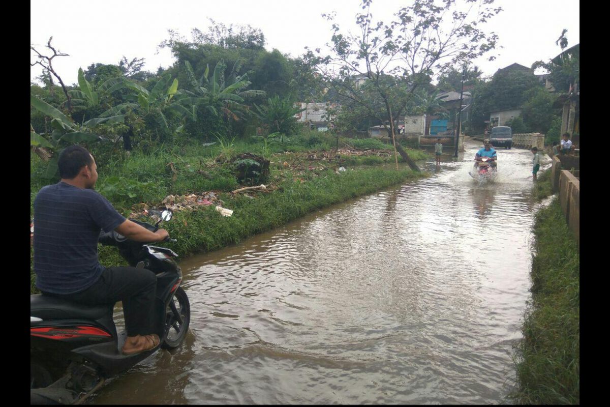 Sepeda motor mencoba melintasi Jalan Mawar RT 003 RW 004, Kelurahan Pasir Putih, Kecamatan Sawangan, Depok yang tergenang luapan air Kali Pesanggrahan, Rabu (14/2/2018).