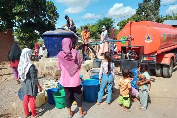 Petugas BPBD membagikan air bersih pada warga terdampak kekeringan di Bima, NTB. 