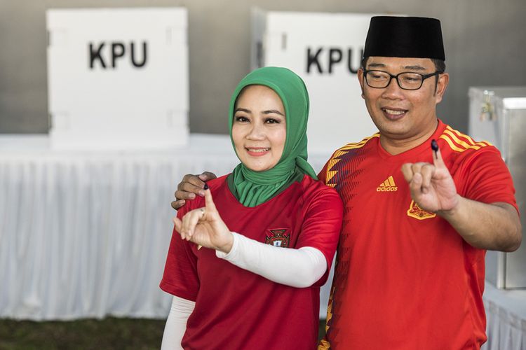 Calon gubernur Jawa Barat nomor urut satu Ridwan Kamil (kanan) bersama istri Atalia Praratya (kiri) menunjukkan tinta pada jari seusai menggunakan hak pilih, di TPS 21 Bandung, Jawa Barat, Rabu (27/6/2018). Pilgub Jabar diikuti empat pasang cagub dan cawagub dengan jumlah daftar pemilih tetap (DPT) sebanyak 31.735.133 pemilih.