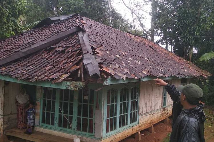 Seorang petugas melihat rumah rusak bagian atapnya terdamapak hujan angin di Desa Cibaregbeg, Sagaranten, Sukabumi, Jawa Barat, Minggu (27/2/2022).