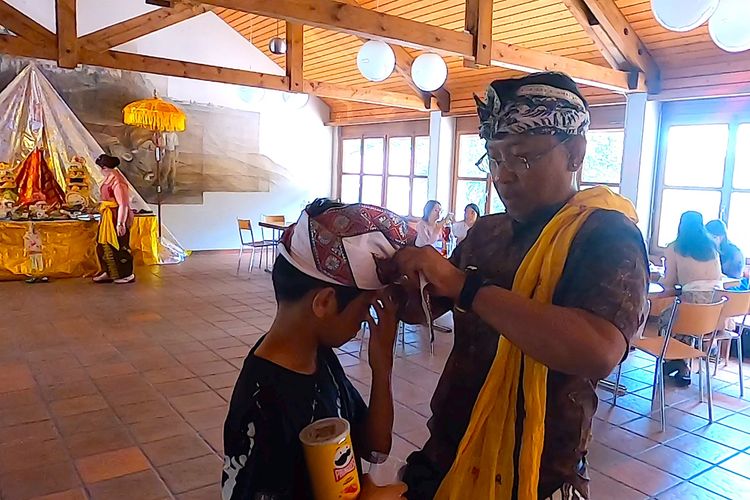 Gede Suarthana, sedang menyiapkan udeng anaknya dalam peringatan Hari Raya Kuningan di Desa Hilfikon, Kota Aarau, Swiss, Sabtu (18/6/2022).