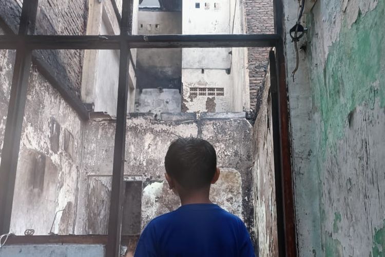 Seorang anak laki-laki yang tinggal di wilayah permukiman padat penduduk di Kampung Pulo, Kampung Melayu, Jatinegara saat melihat sisa bangunan yang habis dilahap api. Akibat kebakaran yang terjadi pada Minggu (25/12/2022) tersebut, puluhan rumah habis dilahap api.