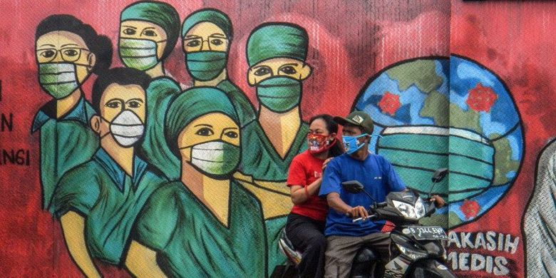 Pengendara motor melintas di depan mural tentang pandemi virus corona atau COVID-19 di Jalan Raya Jakarta-Bogor, Depok, Jawa Barat, Jumar (3/4/2020). Mural tersebut ditujukan sebagai bentuk dukungan kepada tenaga medis yang menjadi garda terdepan dalam menghadapi COVID-19 di Indonesia. 