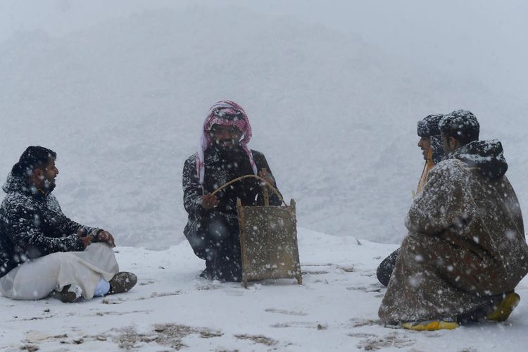 Pengunjung menikmati hujan salju yang turun di wilayah Tabuk, Arab Saudi, Sabtu (1/1/2022). Setiap tahun, hujan salju membawa turis dari seluruh Kerajaan Arab Saudi ke wilayah tersebut. Akibat pandemi Covid-19, mungkin akan ada lebih sedikit pengunjung yang datang ke wilayah Tabuk untuk melihat salju.