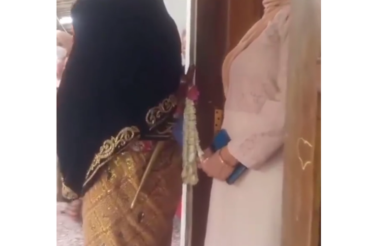 Tangkapan layar video viral seorang perempuan mengambil secara diam-diam bunga melati mempelai pengantin pria.