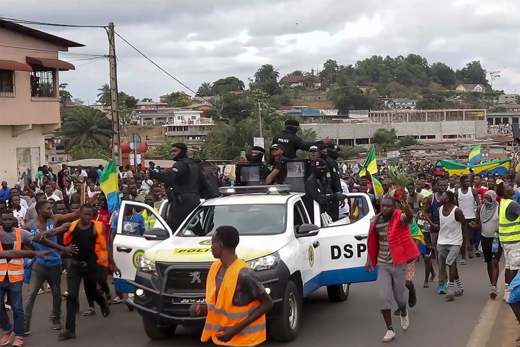 Pendukung kudeta Gabon bersorak bersama polisi di ibu kota Libreville pada Rabu (30/8/2023). Kudeta militer Gabon terjadi setelah puluhan tentara mengumumkan pembatalan hasil pemilu yang memenangkan Presiden Ali Bongo untuk melanjutkan 55 tahun kekuasaan keluarganya.