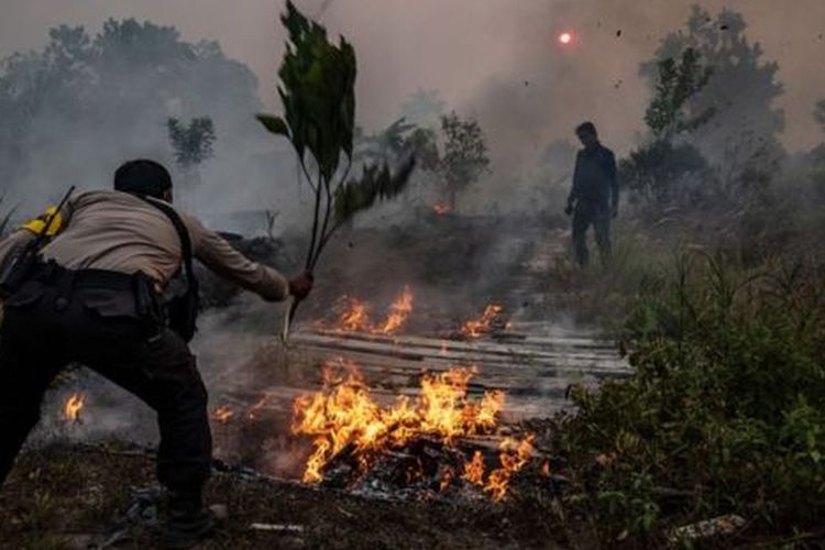 Seorang polisi berusaha memadamkan api yang menyala di suatu lahan di Palangkaraya, 14 September 2019. 