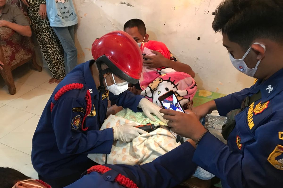 Anggota Suku Dinas Penanggulangan Kebakaran dan Penyelamatan Jakarta Selatan melakukan pemotongan cincin di tangan Ratna yang bengkak akibat luka bakar pada Senin (22/12/2020) sore.