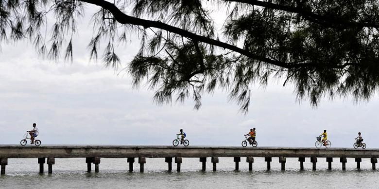 Pengunjung bersepeda menyusuri Jembatan Cinta di Pulau Tidung, Sabtu (14/3/2015). Keindahan pantai di Pulau Tidung, Kepulauan Seribu, menjadi salah satu daya tarik wisatawan untuk berkunjung ke pulau ini.