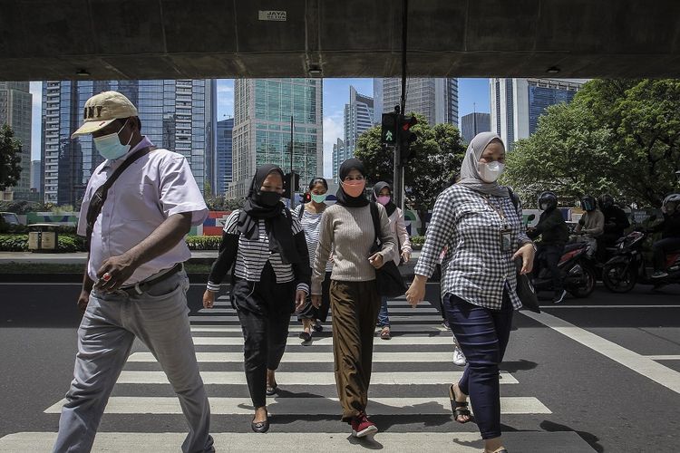 Pekerja menyeberang jalan di kawasan Karet Kuningan, Jakarta, Selasa (22/2/2022). Pemerintah menetapkan Pemberlakuan Pembatasan Kegiatan Masyarakat (PPKM) di Jawa-Bali kembali diperpanjang hingga 28 Februari 2022 sebagai salah satu langkah antisipatif penanggulangan COVID-19 di tengah merebaknya varian Omicron di Indonesia. ANTARA FOTO/Dhemas Reviyanto/foc.