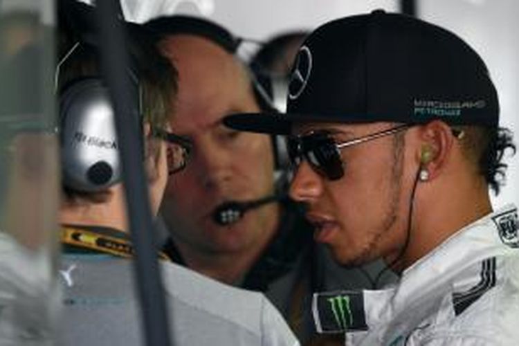 Pebalap Mercedes asal Inggris, Lewis Hamilton (kanan), berbicara kepada mekanik saat sesi latihan pertama GP Jerman di Sirkuit Hockenheim, Jumat (18/7/2014).