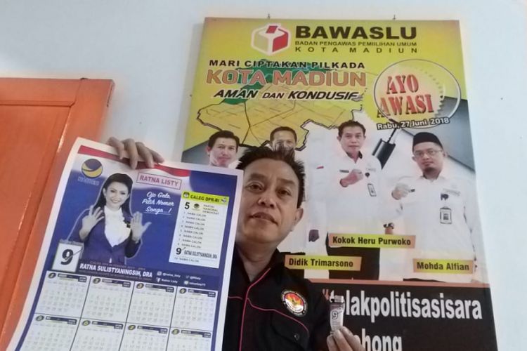 Ketua Bawaslu Kota Madiun, Kokok Heru Purwoko menunjukkan alat peraga kampanye berupa kalander dan korek api yang dibagikan tim saat artis Ratna Listy berkampanye di Pasar Spoor, Kota Madiun, Jawa Timur.