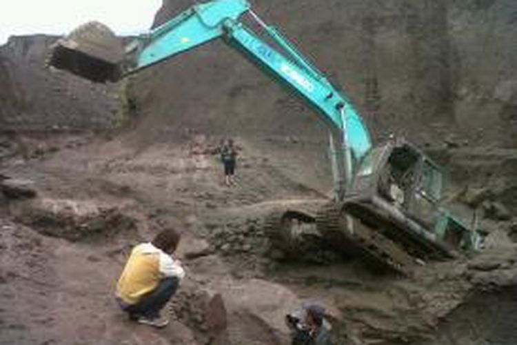 Sebuah alat berat tertimbun material banjir lahar dingin di Sungai Gendol, Kecamatan Cangkringan, Kabupaten Sleman, DI Yogyakarta, Minggu (19/1/2014).