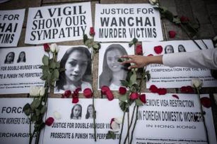 An Indonesian migrant worker lays rose pertals over the pictures of murder victims in Hong Kong on November 9, 2014.  British banker Rurik Jutting, 29, has been charged with murdering Indonesians Sumarti Ningsih and Seneng Mujiasih after police found their mutilated bodies in his upmarket Hong Kong apartment on November 1.     AFP PHOTO / Philippe Lopez