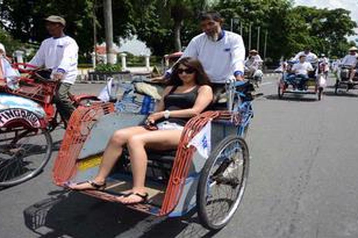 Wisatawan asing asal Belgia menaiki becak untuk menikmati suasana kota di kawasan Titik Nol, Yogyakarta, Selasa (2/4/2013). Berwisata dengan becak merupakan salah satu paket wisata yang banyak diminati wisatawan asing saat berkunjung di Yogyakarta.

