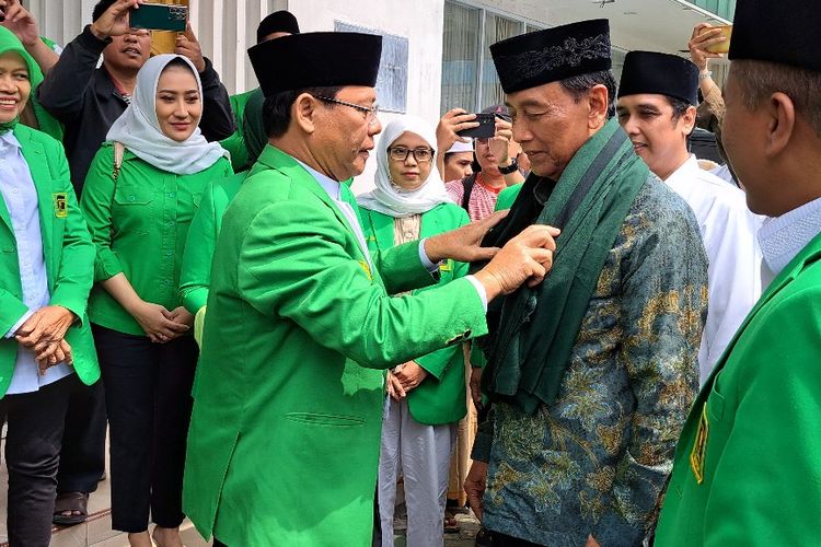 Plt Ketua Umum Partai Persatuan Pembangunan (PPP) Muhammad Mardioni mengalungkan sorban ke Ketua Dewan Pertimbangan Presiden (Wantimpres) Wiranto di kantor DPP PPP, Jakarta, Senin (1/5/2023).