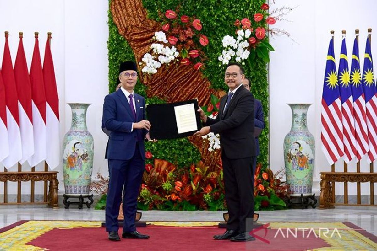 Malaysian Minister of International Trade and Industry Tengku Zafrul Tengku Abdul Aziz (left) and head of the Nusantara Capital (IKN) Authority Bambang Susantono (right) hold a document on investment plans in IKN during a ceremony at Bogor Palace, West Java province, on January 9, 2023. 