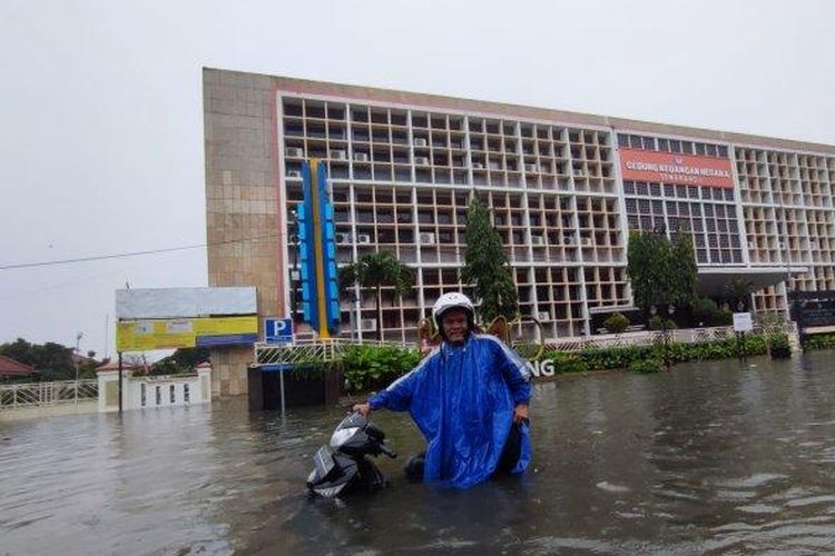 Pekerja kebersihan di Stasiun Tawang, Prasongko saat menerabas banjir untuk berangkat kerja, Kota Semarang, Sabtu (31/12/2022)