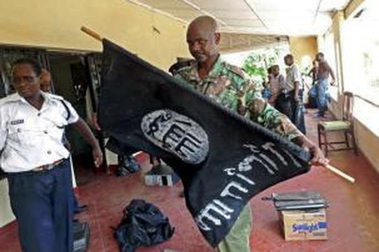 Seorang prajurit Kenya membawa bendera hitam Al-Shabab dalam penggerebekan di dua buah masjid di kota Mombasa, Senin (17/11/2014).