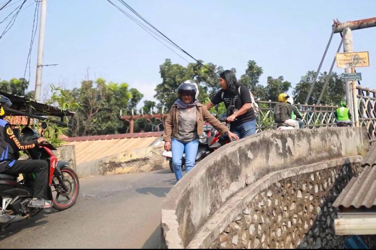 Pengendara bernama Dede (45) memilih untuk menuntun motor saat hendak menuruni Jalan Jembatan Gantung Pasar Minggu, Pejaten Timur, Pasar Minggu, Jakarta Selatan. 