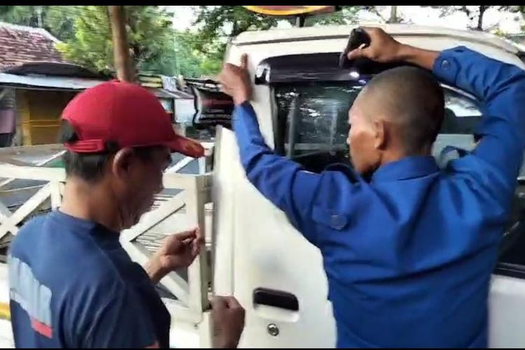 Petugas Damkar berusaha memasukkan kawat ke dalam kaca untuk membuka pintu mobil terkunci di Pamekasan, Jumat (1/8/2025)