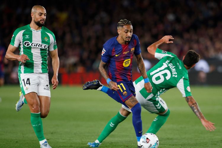 Sofyan Amrabat dan Valentin Gomez mengapit Raphinha dalam pertandingan sepak bola Liga Spanyol antara FC Barcelona vs Real Betis di Stadion Camp Nou di Barcelona pada 17 Mei 2026. (Foto oleh JAIME REINA / AFP)