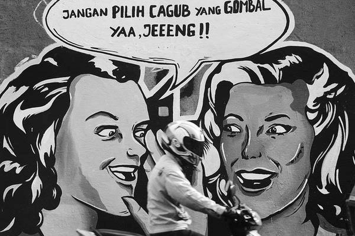 Warga melintas di depan mural tentang ajakan  untuk memilih calon gubernur dan wakil gubernur yang tidak mengobral janji di salah satu tembok di Jalan Daan Mogot, Jakarta Barat, Selasa (3/7). Ajakan itu juga untuk mengampanyekan agar warga memilih dengan menggunakan hati.