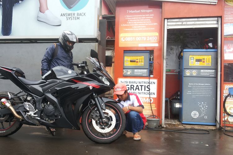 Seorang petugas outlet pengisian ban dengan nitrogen di salah satu SPBU Pertamina di Jalan Margonda, Depok sedang melayani pelanggan pada Kamis (8/2/2018).