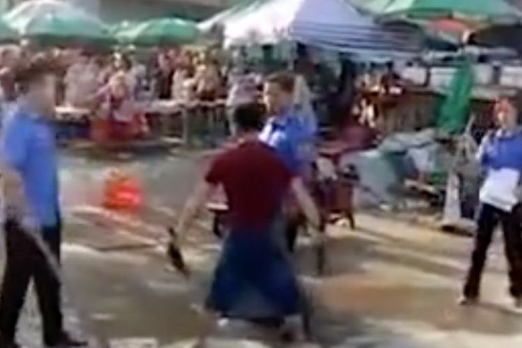 Seorang tukang daging menghadapi tiga orang parapolisi atau Chengguan di Yulin, China, sambil membawa pisau daging. Dia mengamuk setelah timbangannya disita.