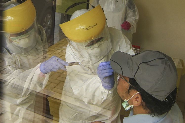 西ジャワ州デポック市チマンギスでスワブテスト（拭き取り検査）によって患者を検査する医療従事者