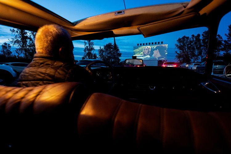 Seorang pria dari dalam mobil menonton film di Drive-in Cinema di Denia, Spanyol,  Kamis (14/5/2020). Bioskop drive-in dengan konsep menonton film dari dalam mobil yang sempat jaya dahulu kala, kini kembali menjadi tren di berbagai negara karena pandemi virus corona.