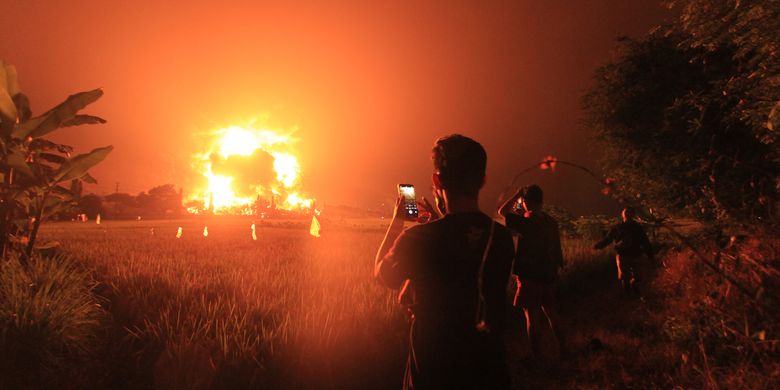 Warga menyaksikan kebakaran di kompleks Pertamina RU VI Balongan, Indramayu, Jawa Barat, Senin (29/3/2021) dini hari. 