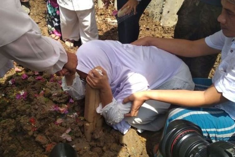 Istri Ewa, menangis di pusara suaminya, Edward Limba, usai prosesi pemakaman di Jalan Cinde Welan Palembang, Rabu (23/8/2017).