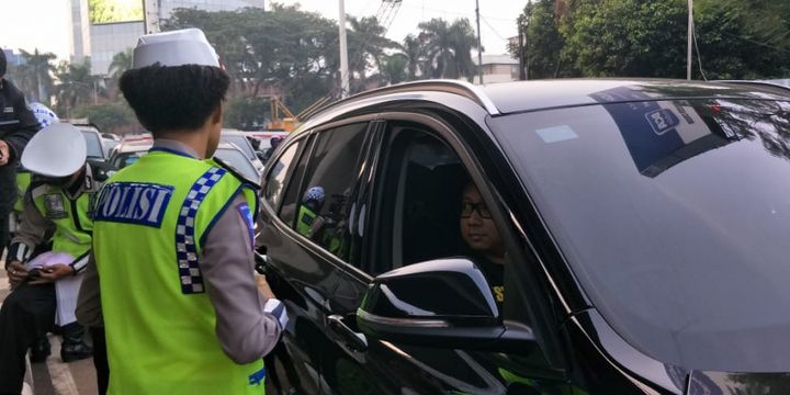Polisi menilang pengendara mobil berpelat genap di Jalan Gatot Subroto, simpang Pancoran, Jakarta Selatan, Rabu (1/8/2018).