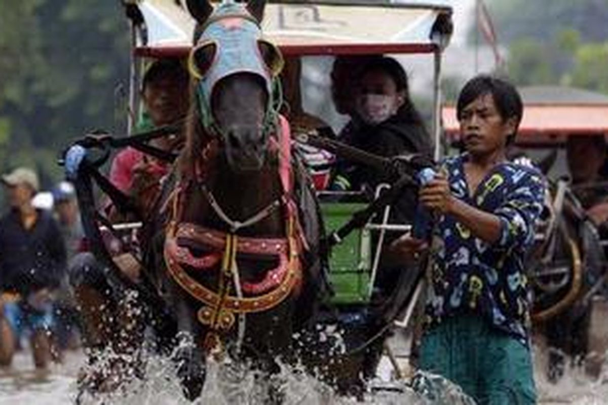 Warga melintasi banjir dengan menggunakan delman di depan Halte Swadaya, Jalan Ciledug Raya, Jakarta Selatan, Selasa (15/1/2013). Banjir ini disebabkan meluapnya Kali Pesanggrahan akibat hujan yang mengguyur sepanjang malam hingga pagi.  