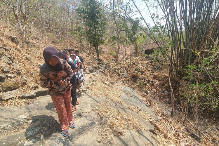 Setelah mengambil air warga berjalan di jalan setapak pinggir jurang di Padukuhan Ngipik, Tegalrejo, Gedangsari, Gunungkidul. Senin (9/10/2023)