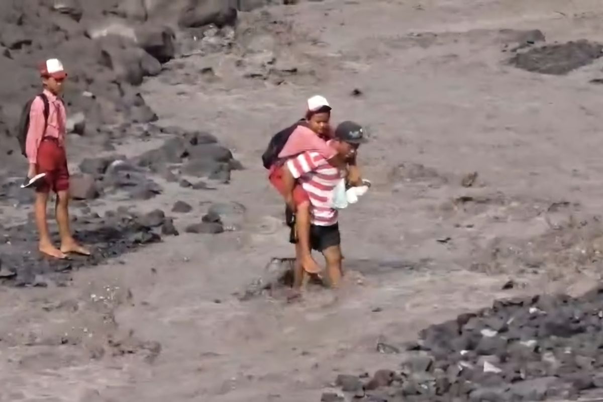 Warga gendong putranya sebrangi banjir lahar hujan Gunung Semeru untuk bisa pergi ke sekolah