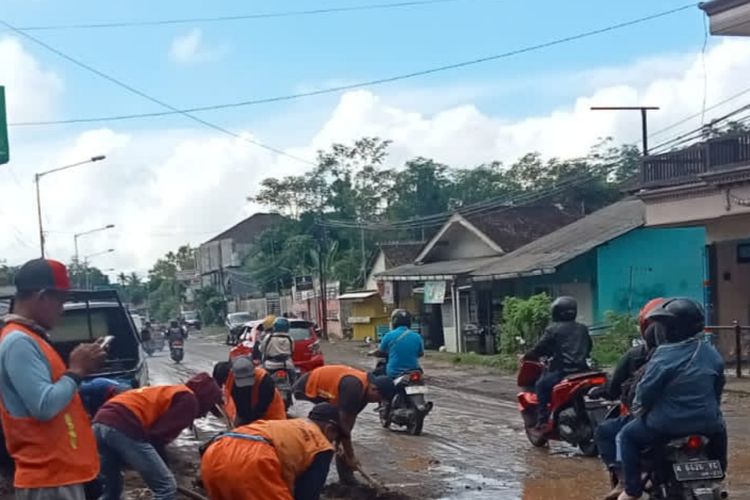 Petugas saat melakukan pembersihan material lumpur dan kerikil di jalan raya Banyuwangi Jember 