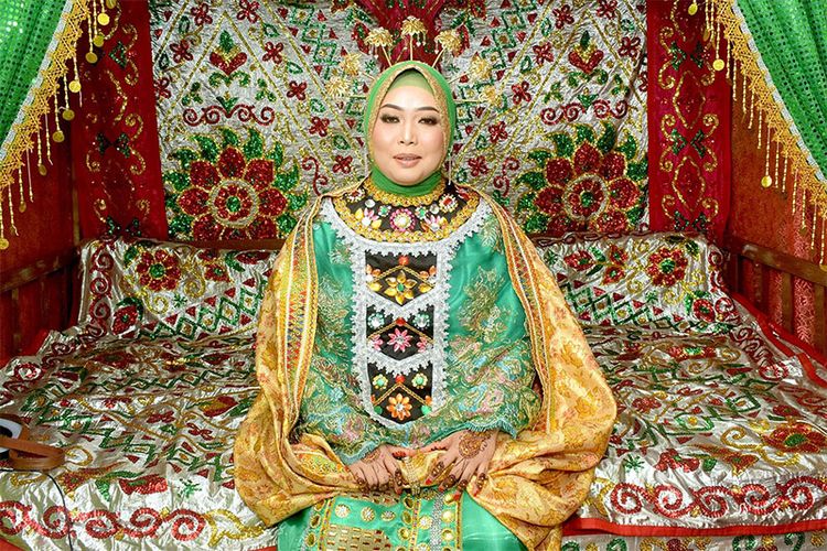Seorang mempelai perempuan Gorontalo yang mengenakan baju adat Wolimomo di kamar pengantin. Baju adat Gorontalo yang sarat makna ini wajib dikenakan saat prosesi pernikahan.