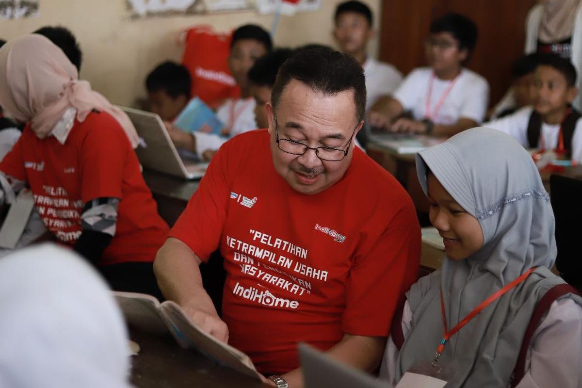 Komisaris Utama Telkom Rhenald Kasali (tengah) memberikan pelatihan internet dasar kepada salah satu siswi Sekolah Dasar dalam program pelatihan keterampilan usaha dan pendidikan masyarakat ?IndiHome untuk Indonesia? di Desa Wukirsari, Bantul, Yogyakarta, Senin (9/12/2019).