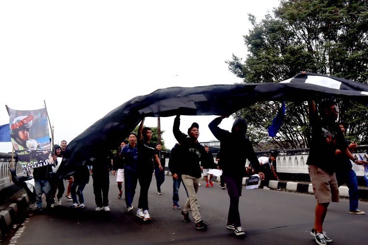 Suporter Arema, Aremania membentangkan spanduk saat melakukan aksi damai Tragedi Kanjuruhan menuntut keadilan yang dilaksanakan di 18 titik Kota Malang, Minggu (20/11/2022) siang.