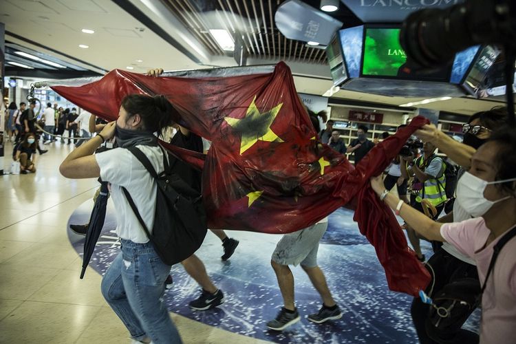 Massa pro-demokrasi melecehkan bendera China dalam aksi di pusat perbelanjaan di Sha Tin, Hong Kong, Minggu (22/9/2019).