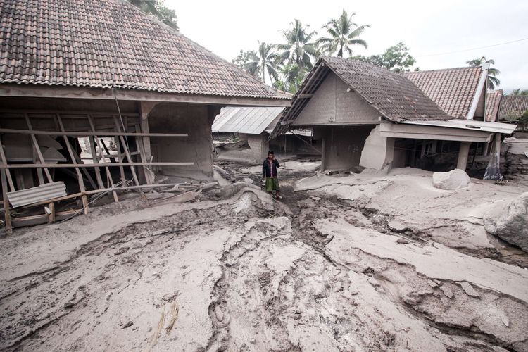 Warga melintas di rumah yang rusak akibat abu vulkanik letusan Gunung Semeru di Desa Sumber Wuluh, Lumajang, Jawa Timur, Minggu (5/12/2021). Akibat letusan Gunung Semeru tersebut sedikitnya puluhan rumah rusak.