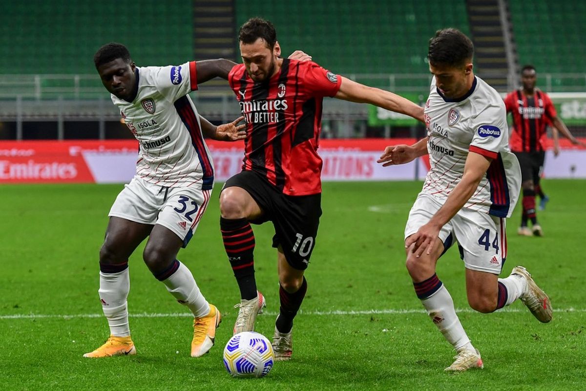 Hakan Calhanoglu (tengah) diapit Alfred Duncan (kiri) dan Andrea Carboni pada laga pekan ke-37 Liga Italia antara AC Milan dan Cagliari di Stadion San Siro, 16 Mei 2021. 