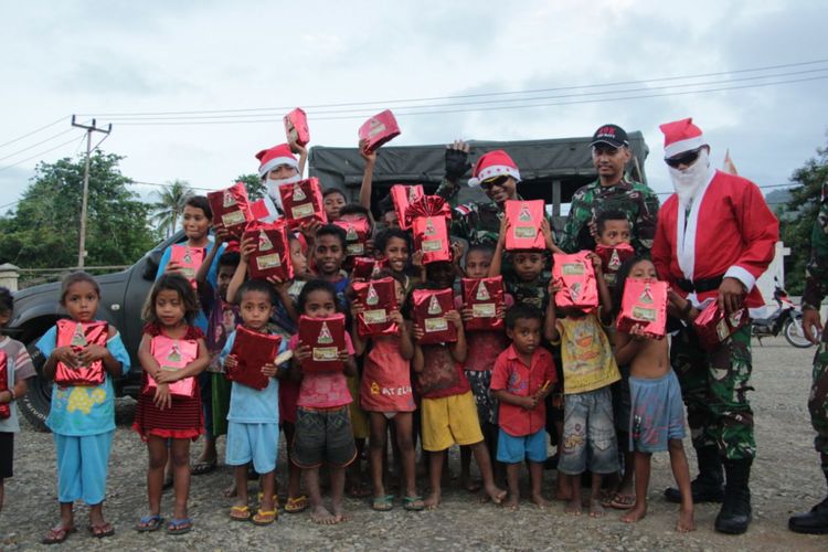 TNI dari Satgas Pamtas RI - Timor Leste Yonif Raider 408/Sbh, mengenakan kostum Santa Klaus, sedang memberikan kado Natal buat anak-anak di perbatasan 