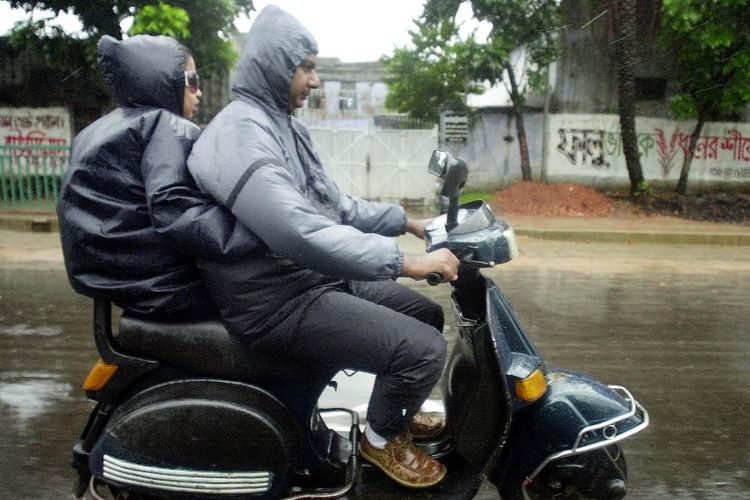 Dua warga mengendarai sepeda motor secara berboncengan melintasi jalan raya di kota Dhaka, Bangladesh.