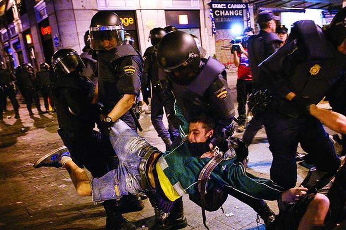 Polisi mengangkat seorang demonstran yang nekat bertahan di alun-alun Puerta del Sol di Madrid, Minggu (13/5) dini hari.  Ribuan rakyat Spanyol kembali turun ke jalan sejak Sabtu untuk memprotes angka pengangguran yang tinggi dan prospek ekonomi yang suram di Spanyol. Pekan ini, gerakan protes di Spanyol genap berusia satu tahun, dan kondisi perekonomian di negara itu tak kunjung membaik. 