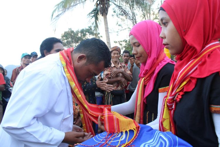 Dua perempuan muslim mengalungkan selendang congkar kepada Imam Katolik, Pastor Rikardus Karno, Projo di Kampung Toleransi Puncak Liur, Desa Ranamese, Kecamatan Sambirampas, Kabupaten Manggarai Timur, Flores, Nusa Tenggara Timur.