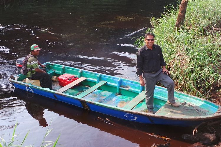 Mahyudin berdiri di atas salah satu perahu yang ia sewakan kepada Riau Andalan Pulp and Papper. Tak lagi mencuri kayu, kini ia mendapat kesempatan kerja sama dengan RAPP juga bantuan pinjaman modal usaha.